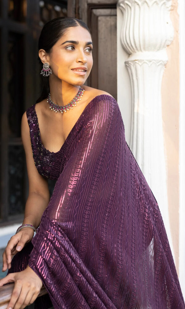 A close-up image of a wine-colored saree adorned with sparkling sequin work, adding shimmer and elegance to the fabric