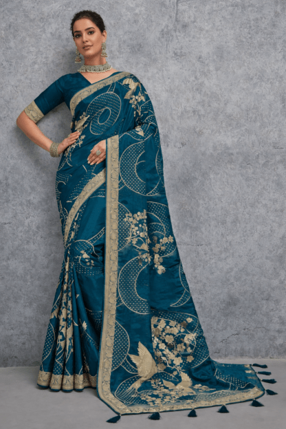 Teal blue Banarasi soft silk saree with gold zari woven floral and bird motifs, rich traditional border and designer pallu, perfect for wedding and festive wear.