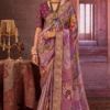 Woman wearing a lavender chinon silk saree with multicolor floral print and gold woven border styled with traditional necklace and earrings.