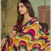Woman seated in multicolor abstract wave print georgette saree with pink blouse and sequin border