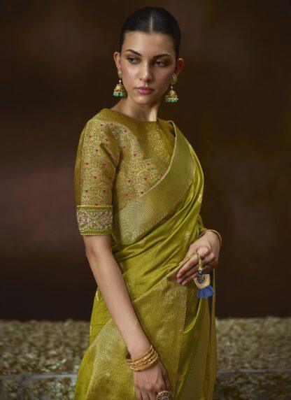 Woman wearing olive green zari woven silk saree with meenakari border and embroidered blouse