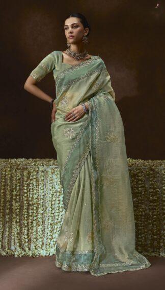Woman wearing pistachio green organza saree with zari embroidery and scalloped border
