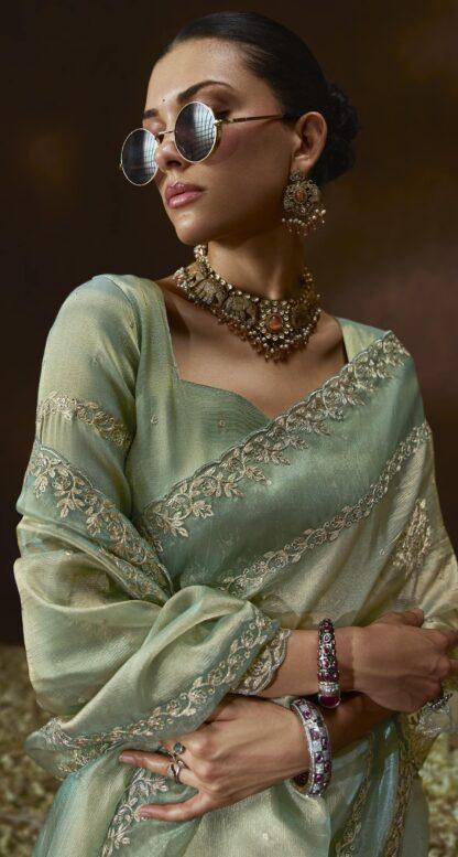 Woman wearing pistachio green organza saree with zari embroidery and scalloped border