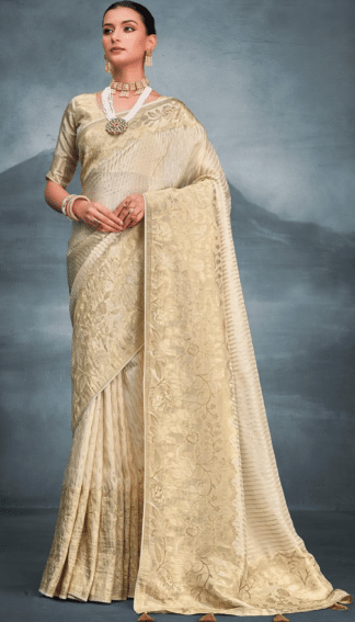 Woman wearing cream gold zari woven tissue silk saree with floral pallu and pearl jewellery