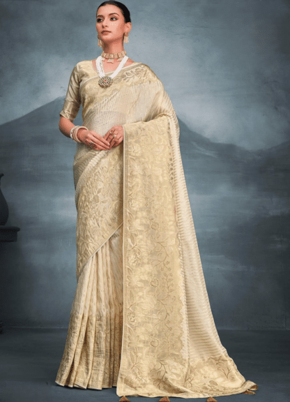 Woman wearing cream gold zari woven tissue silk saree with floral pallu and pearl jewellery
