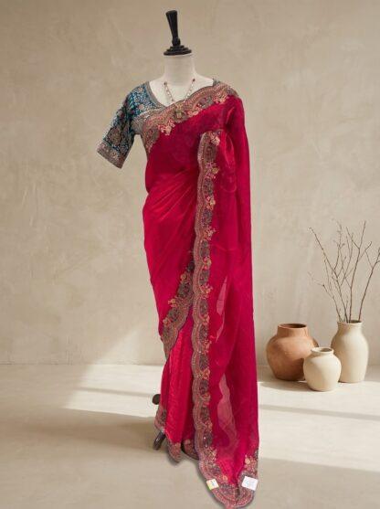 Rani pink saree with scalloped embroidered border and teal blue blouse displayed on a mannequin at Sagar Sarees