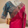 Rani pink saree with scalloped embroidered border and teal blue blouse displayed on a mannequin at Sagar Sarees