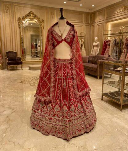 Red bridal lehenga with heavy zari and mirror embroidery and net dupatta on a mannequin at Sagar Sarees