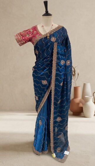 blue saree with zigzag sequin work, embroidered border and contrast pink blouse displayed on a mannequin at Sagar Sarees